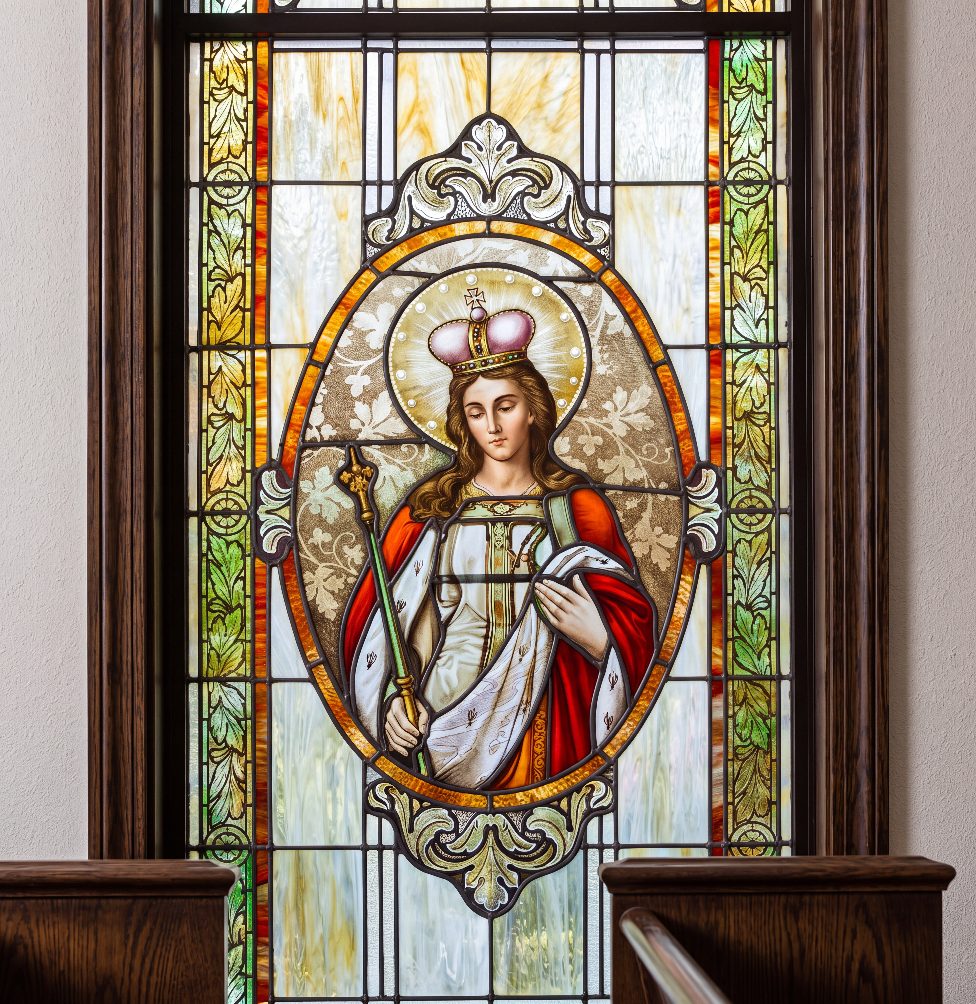 Stained glass window of a crowned saint holding a scepter