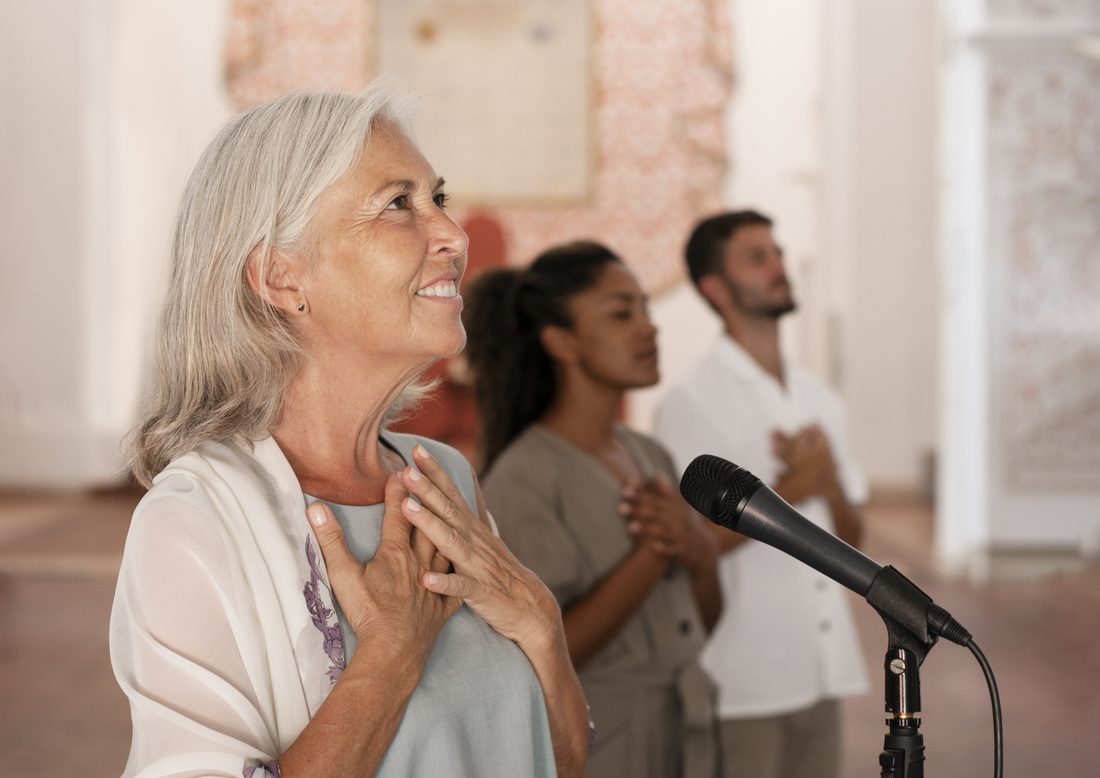 A cantor singing at a microphone with her hand on her heart