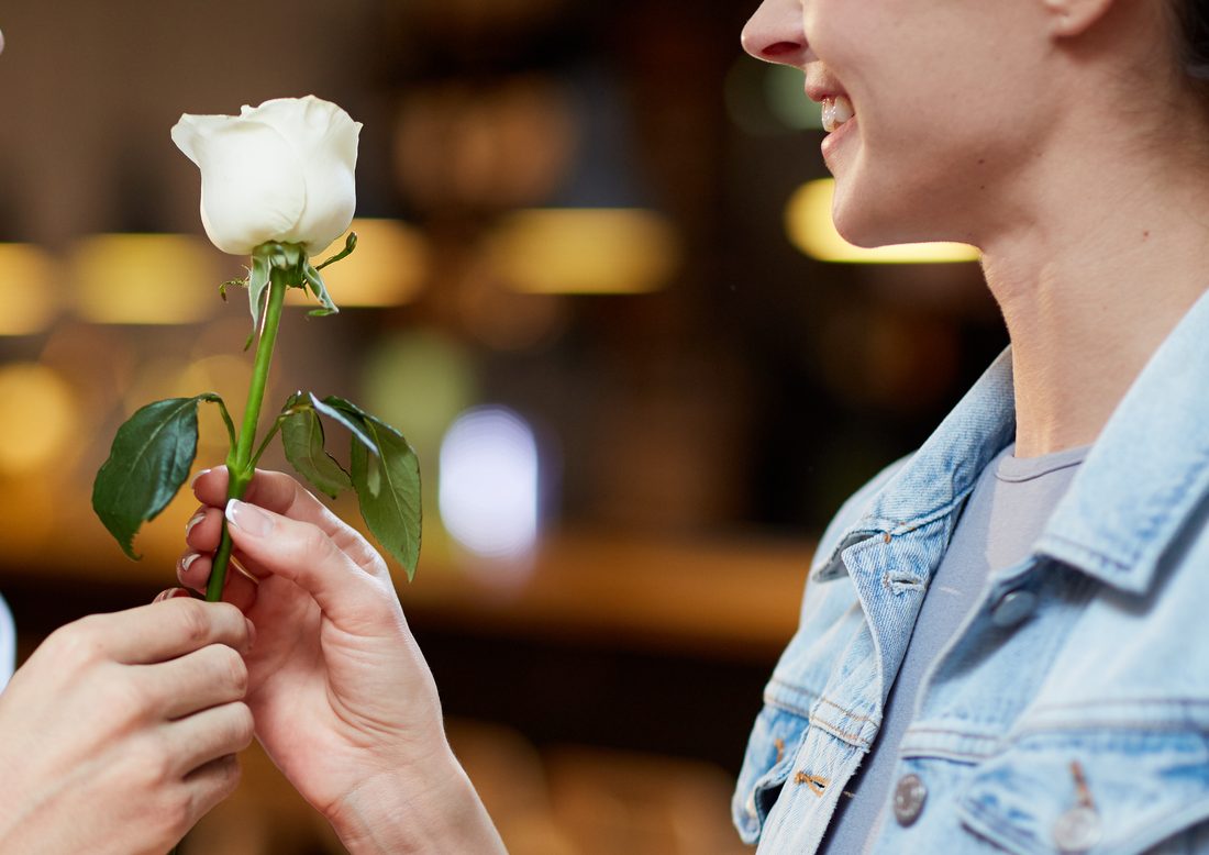 Hands passing a white rose
