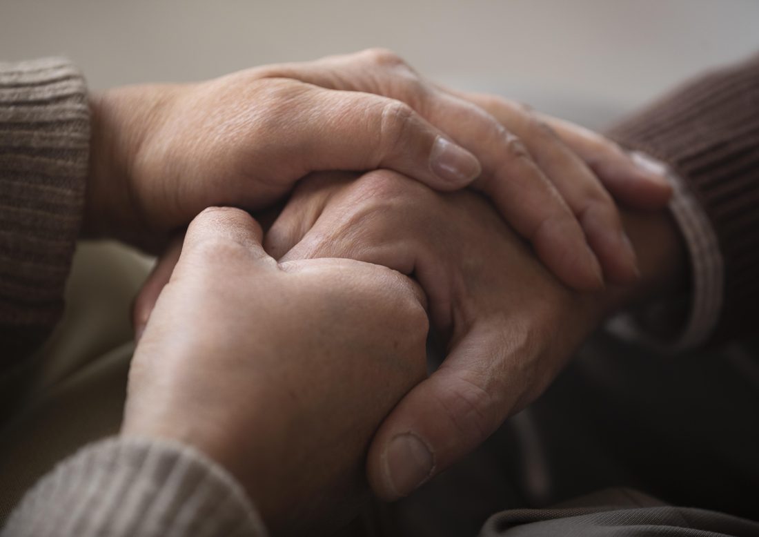 Hands gently holding an older person's hand