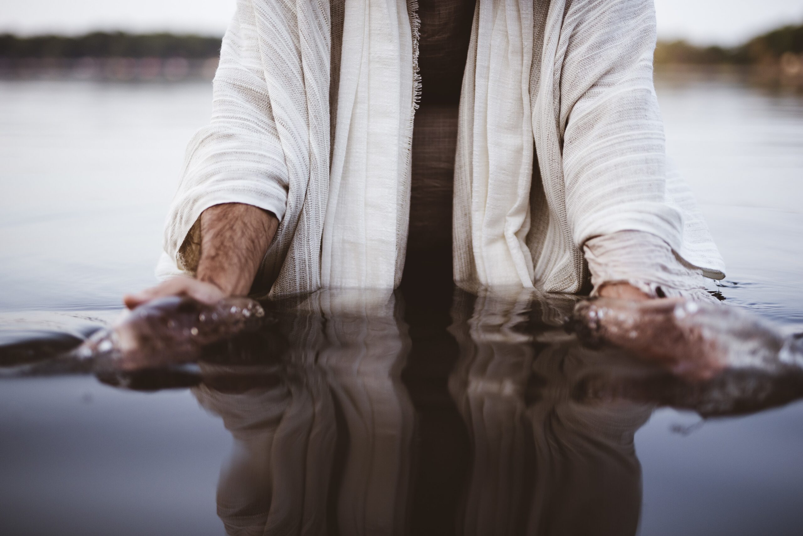 A person in a white robe standing in water