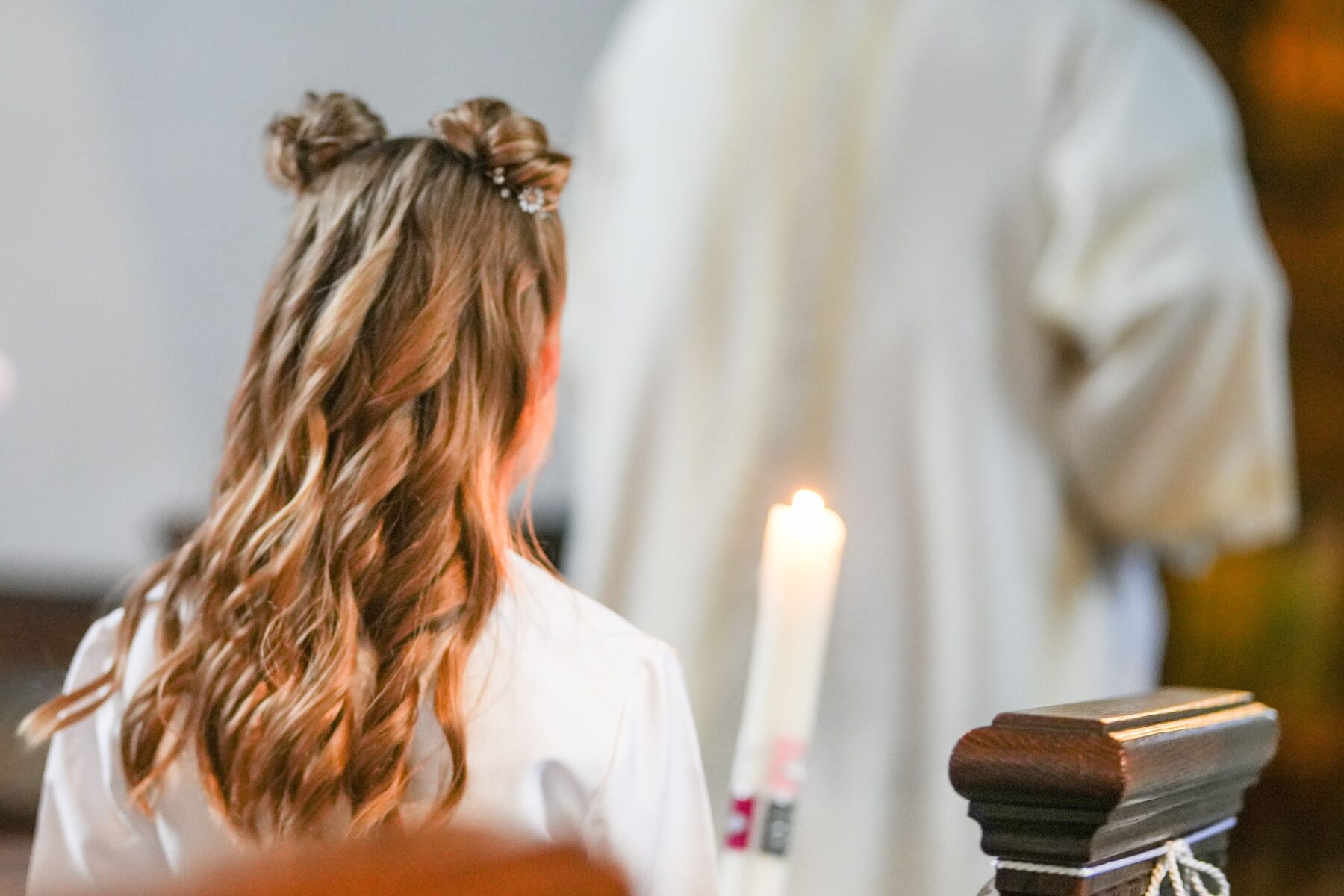 A girl in a white dress beside a lit candle