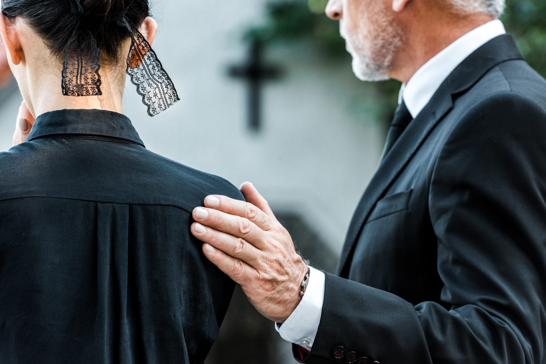 A man comforting a grieving woman with a hand on her shoulder