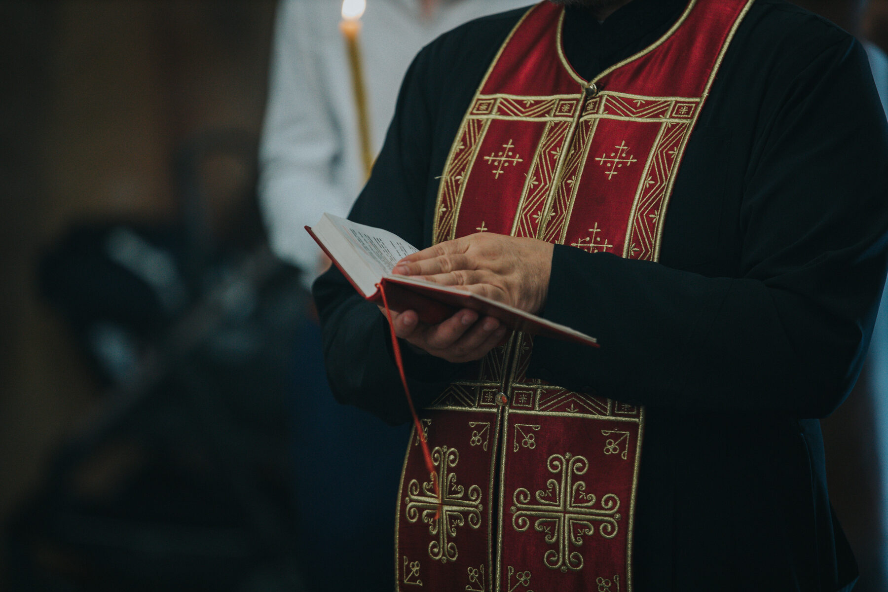 A priest in red vestments reading from a book