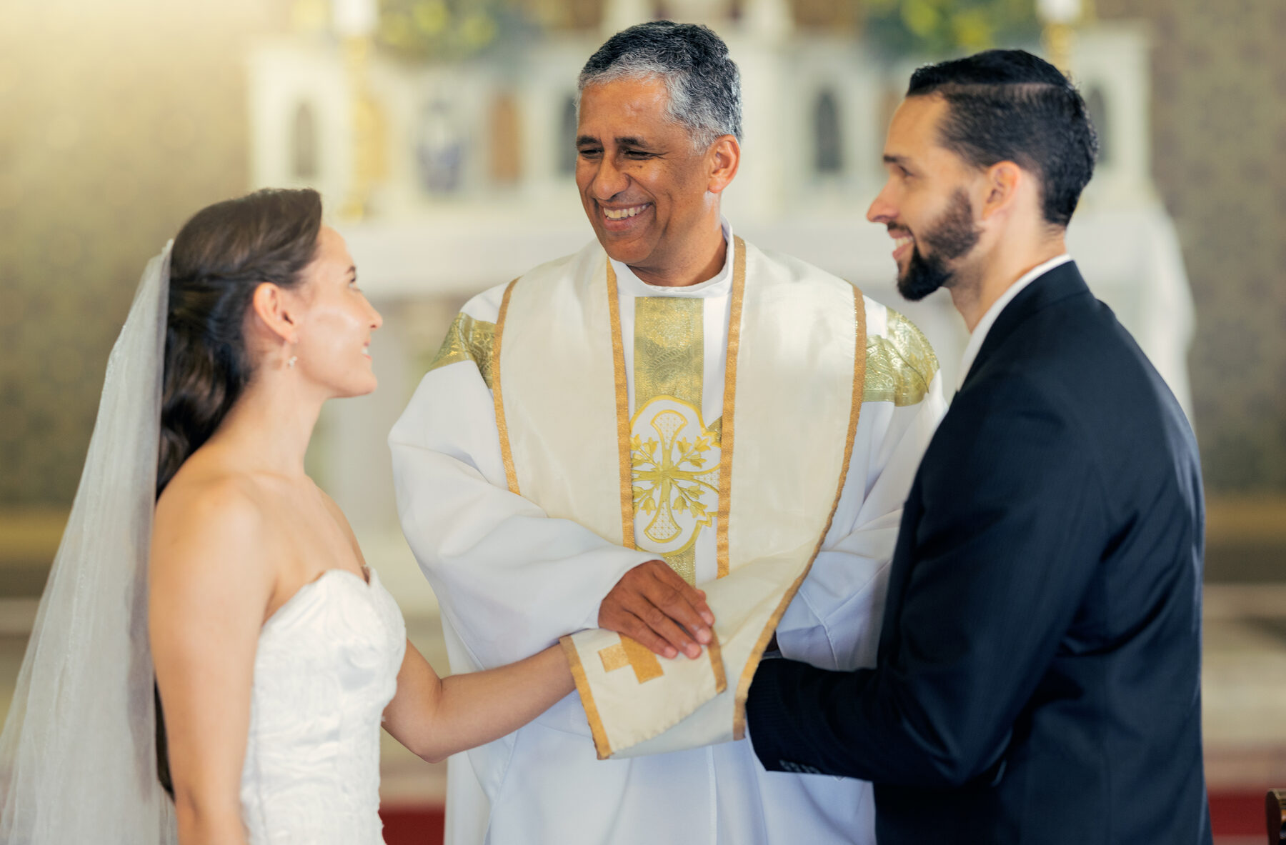 A priest with a bride and groom at the altar