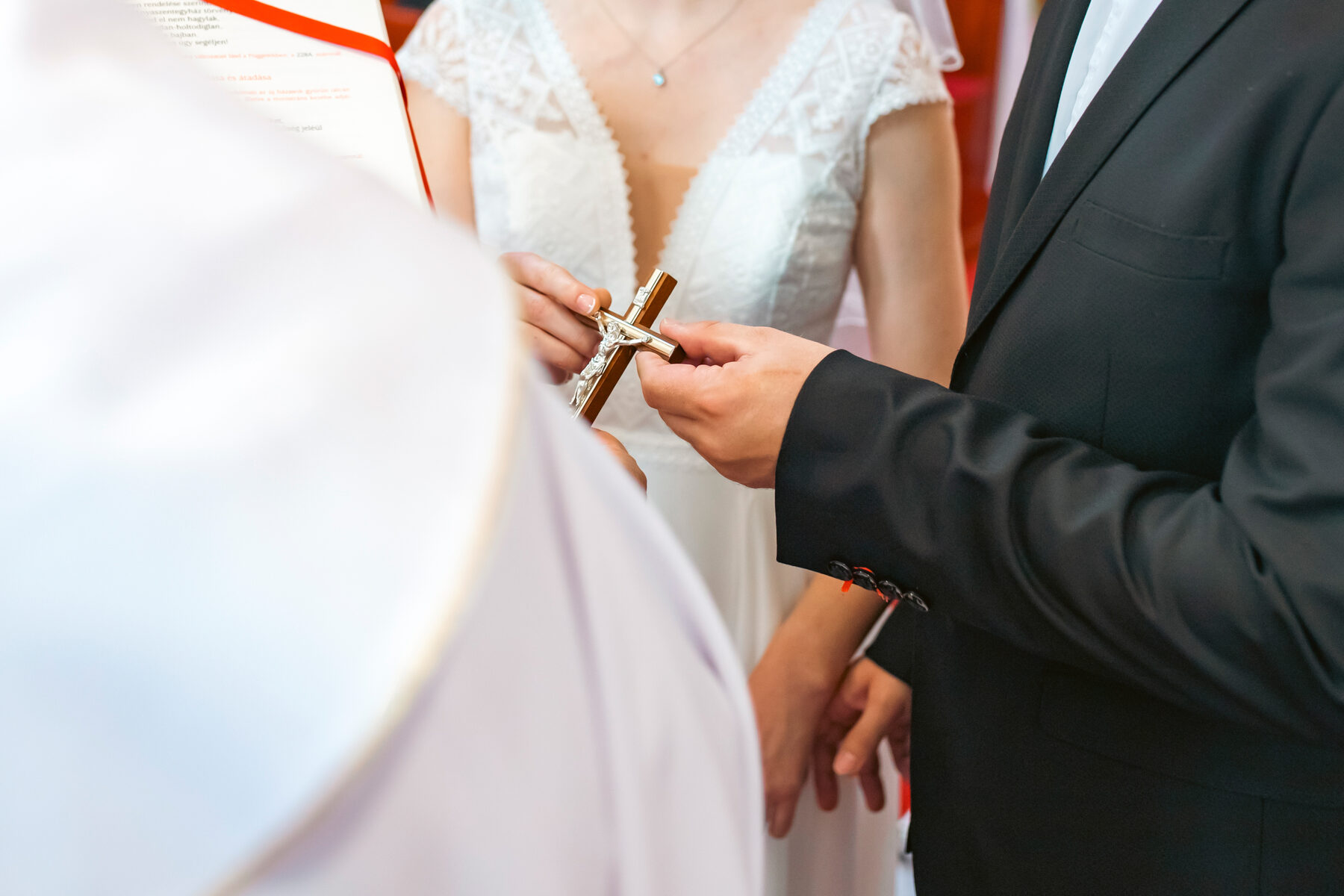 A bride and groom holding a crucifix during the ceremony
