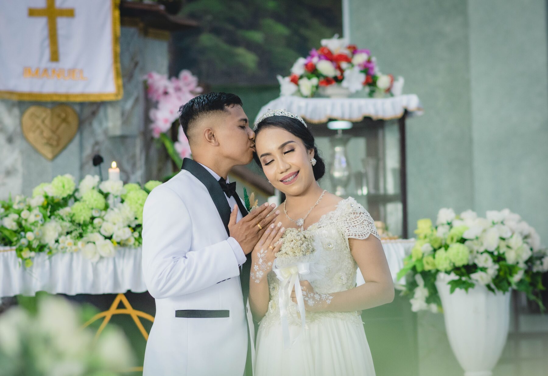 A groom kissing his bride on the forehead