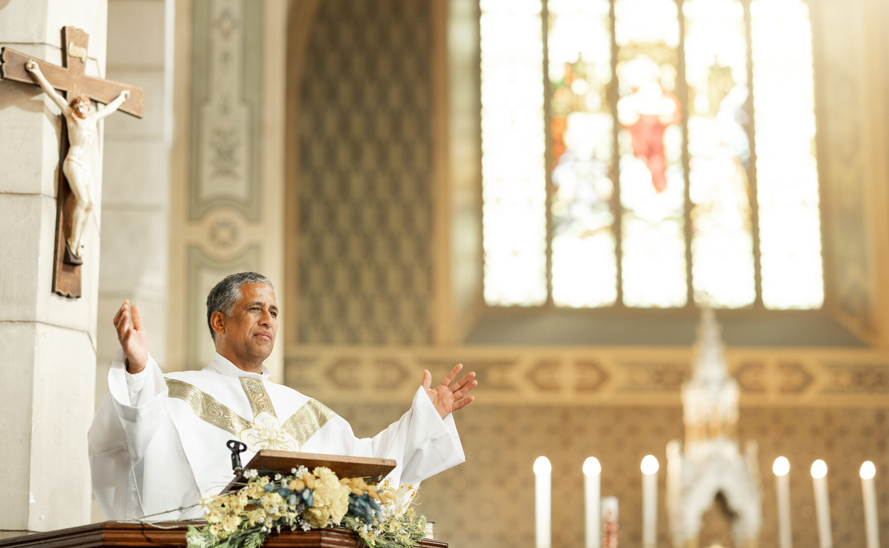 A priest at the altar with arms raised in prayer
