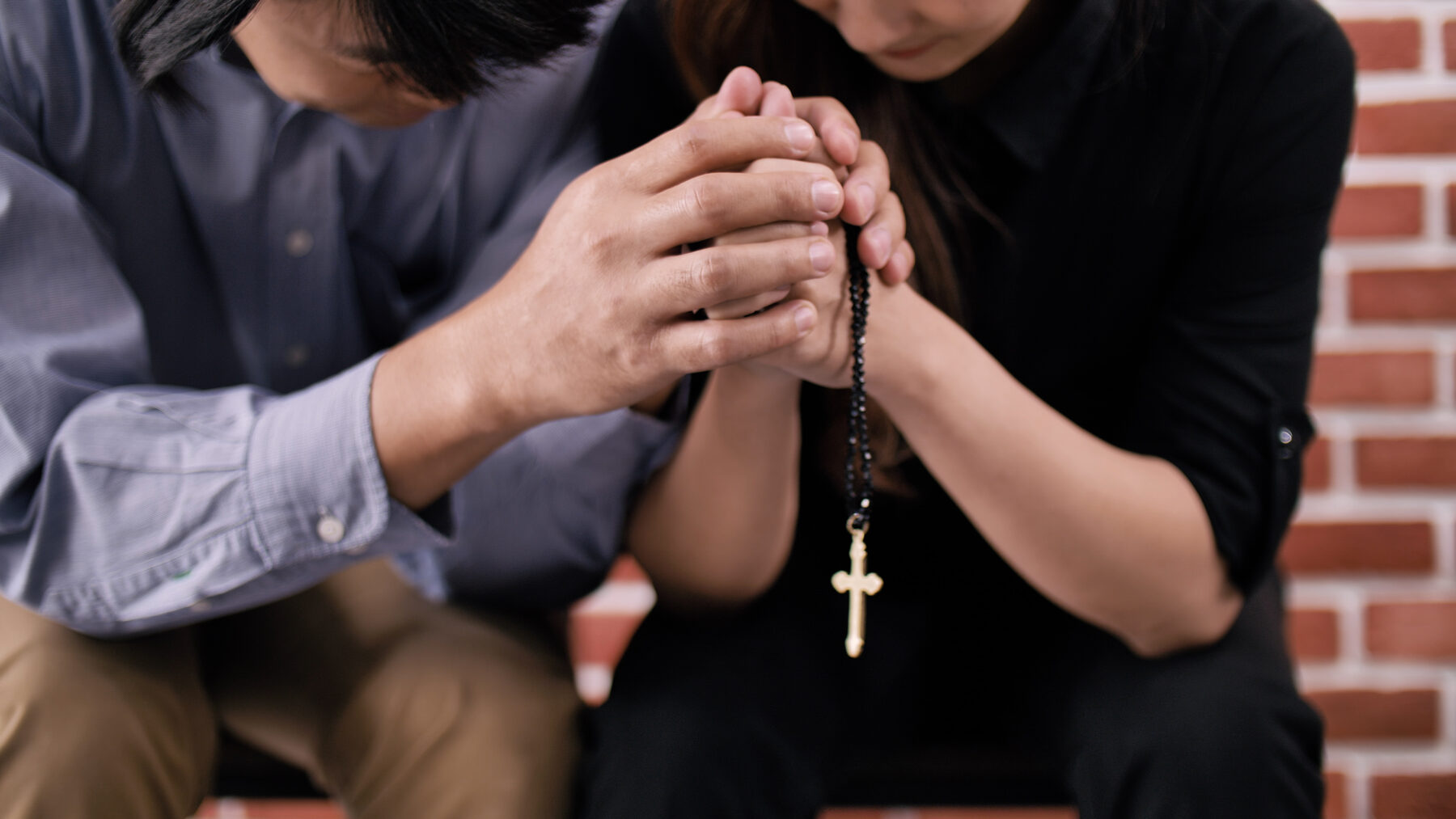 Two people praying together with a rosary